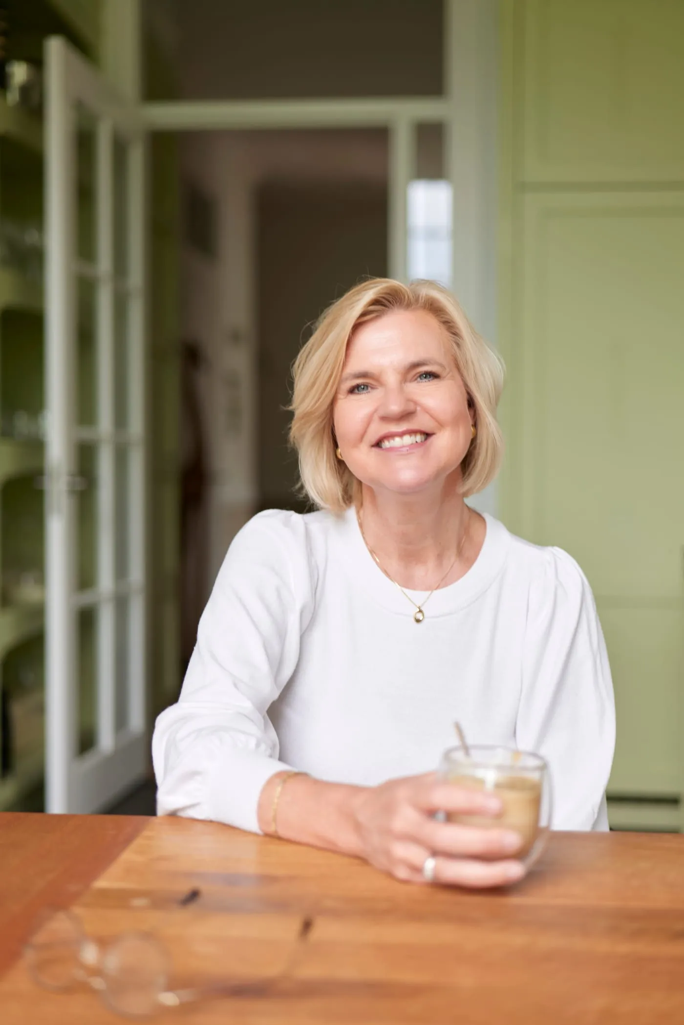 Lisette Brattinga met een kop koffie aan de keukentafel